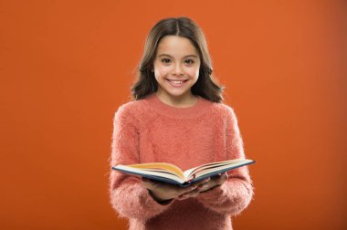 Kız tutun kitap turuncu arka plan üzerinde hikaye okuyun. Çocuk kitap okuma keyfini çıkarın. Kitap mağaza konsepti. Harika ücretsiz çocuk kitapları okumak kullanılabilir. Çocuk edebiyatı. Onun için yararlı bilgiler