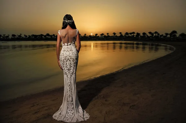 Mujer en vestido blanco en la playa del atardecer — Foto de Stock