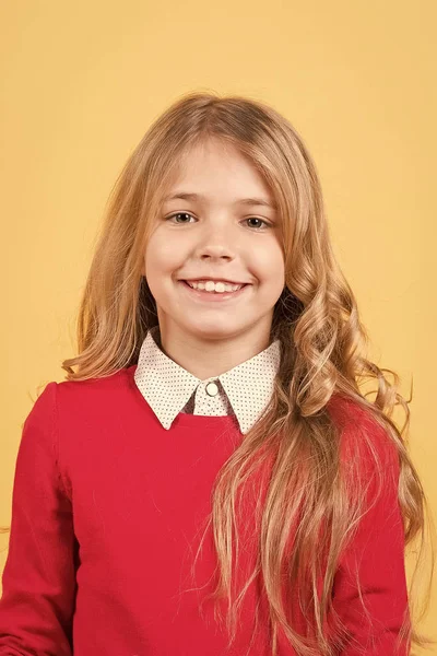 Ребенок с вьющимися светлыми волосами в красном свитере — стоковое фото
