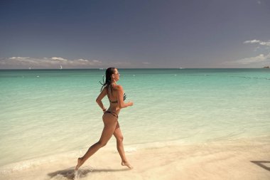 Plajda koşan bikinili kadın.