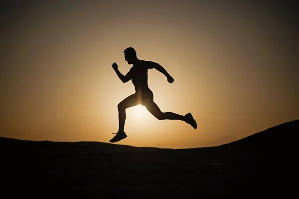 Correndo silhueta homem no céu por do sol — Fotografia de Stock