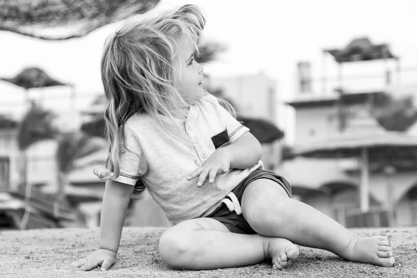 Los niños juegan en la arena. Un niño pequeño se sienta en la playa tropical. Actividad de verano en la playa. Concepto de vacaciones, ocio y relax. Niño con el pelo rubio divertirse al aire libre —  Fotos de Stock