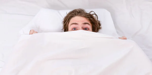 Bare feet of a man peeking out from under the cove. Lazy man happy waking up in the bed rising hands in the morning with fresh feeling relaxed. Happy guy in bed. — Stock Photo, Image