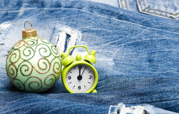 Es hora de celebrar el año nuevo y la Navidad. Celebra la Navidad. Decoración de bolas para árbol de Navidad y reloj despertador sobre fondo denim. Concepto de vacaciones de invierno. Decorar árbol de navidad juguete tradicional — Foto de Stock