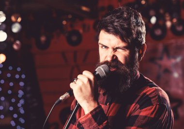 Sakal ve bıyık şarkı şarkıda karaoke ile müzisyen. Rock yıldız kavramı. Adam hevesli yüz tutan mikrofon, şarkı şarkı, karaoke club arka plan. Adam agresif şekilde şarkı söylemeyi seviyor