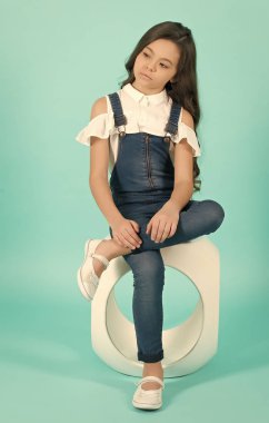 Kot pantolonlu çocuk sandalyede bacak bacak üstüne atıyor.