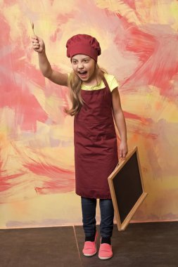 Küçük kız yemek blackboard ile şapkalı.