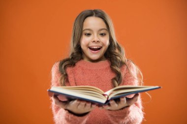 Çocuk kitap okuma keyfini çıkarın. Kitap mağaza konsepti. Harika ücretsiz çocuk kitapları okumak kullanılabilir. Çocuk edebiyatı. Çocuklar için okuma etkinlikleri. Kız tutun kitap hikaye turuncu arka plan üzerinde okuyun.