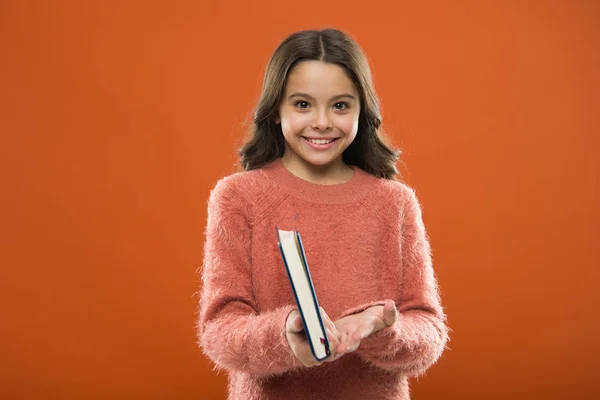 Flickan håller boken Läs historien över orange bakgrund. Barn tycker om att läsa boken. Boken butikskoncept. Fantastiskt gratis barnens böcker finns att läsa. Childrens litteratur. Läsande aktiviteter för barn — Stockfoto