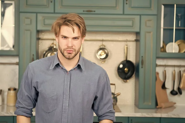 Man with serious face in blue shirt stand in kitchen — Stock Photo, Image