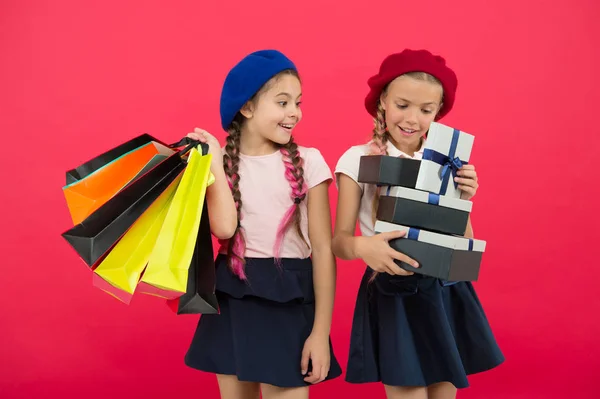购物狂的概念。购物成为乐趣与最好的朋友。孩子们可爱的女学生拿着一堆购物袋。孩子们满意的购物红色背景。痴迷于购物和服装商场 — 图库照片