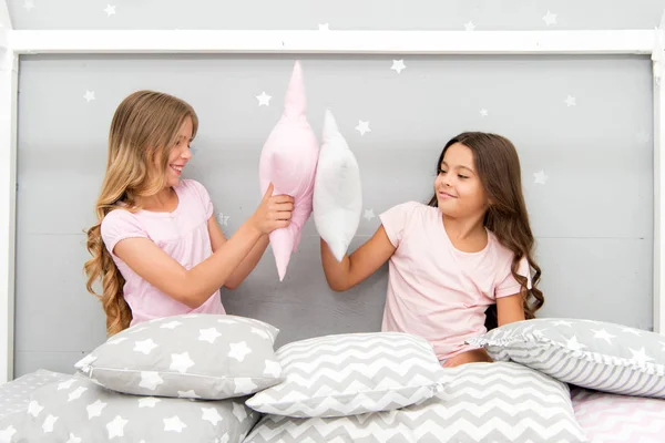 Sisters play pillows bedroom party. Pillow fight pajama party. Evening time for fun. Sleepover party ideas. Girls happy best friends or siblings in cute stylish pajamas with pillows sleepover party