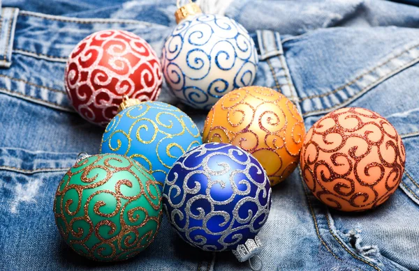 Christmas decorations concept. Pick colorful decorations. Modern christmas decor. Christmas ornaments or decorations on denim pants background. Balls with glitter and shimmering decorative ornaments