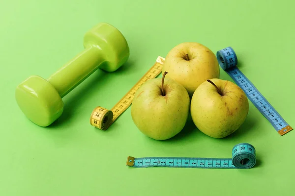 Pattern made of apple fruits near barbell and tape measure