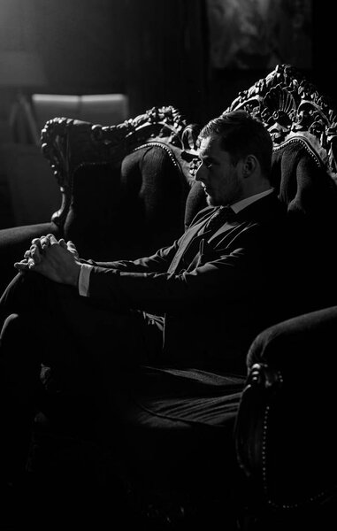 Адвокат с серьезным небритым лицом. Бизнесмен сидит на элегантном винтажном диване и думает. Профессиональный успех, бизнес, мода, концепция богатства. Директор в модном костюме выглядит респектабельно
