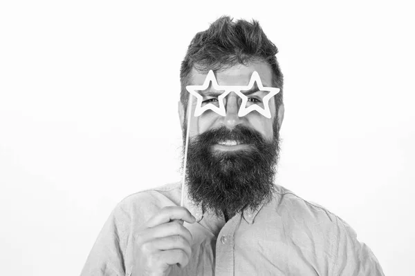 Hipster com barba e bigode no rosto sorridente alegre posando com óculos em forma de estrela, espaço de cópia. Homem detém adereços de festa em forma de estrela óculos, fundo branco, close up. Conceito de super estrela — Fotografia de Stock