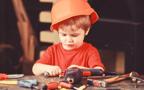 바쁜 얼굴을 하고 있는 아이들은 작업장에서 볼트로 집에서 놀고 있습니다. 꼬마 애는 돈 벌 이 로노는 거야. 딱딱 한 모자를 쓰고 헬멧을 쓰고 건설업자나 수공예 인으로 헬멧을 쓰고 노는아이. 수공예 개념 — 스톡 사진