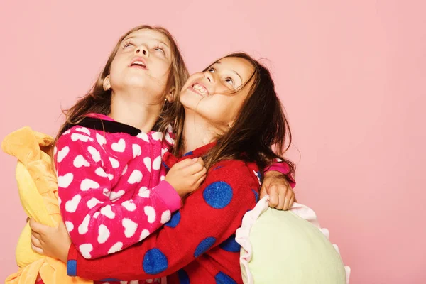 Mädchen in bunten Pyjamas halten lustige bunte Kissen in der Hand — Stockfoto