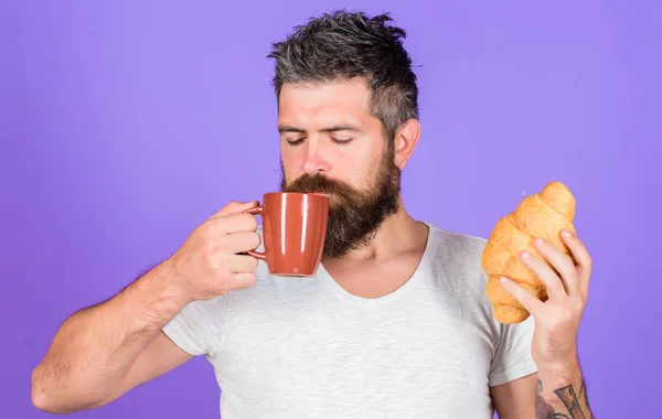 Homme commencer la matinée avec une tasse de café et croissant frais. Hipster barbu profiter du petit déjeuner boire du café. Concept de tradition matinale. Mais d'abord le café. Savourez chaque gorgée de café. Match parfait — Photo