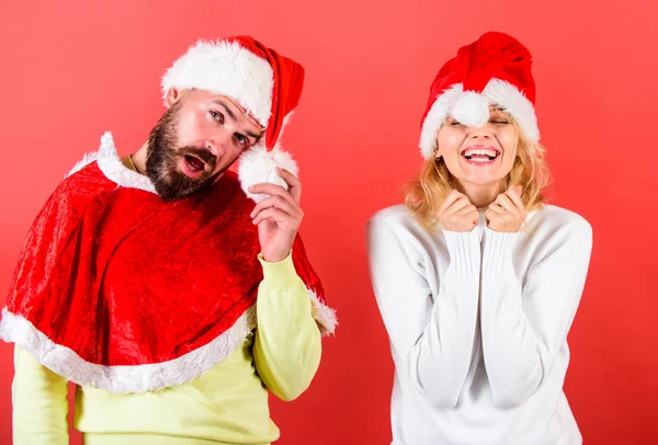 Couple célébrer Noël vacances d'hiver fête. Homme avec barbe et femme en chapeau de Père Noël avec fond rouge pompon. Mascarade de Noël ou concept de carnaval. Couple visage joyeux célébrer Noël — Photo