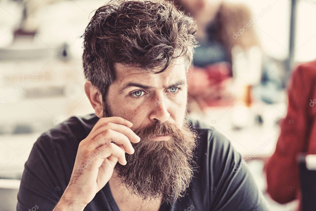 Man with beard and mustache sits outdoor at cafe terrace. Bearded man on calm face looks sad and troubled. Hipster with beard going through difficult times. Sadness and problems concept