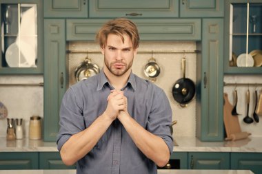 Adam ciddi bir yüz ile stand ile mutfakta katlanmış parmak