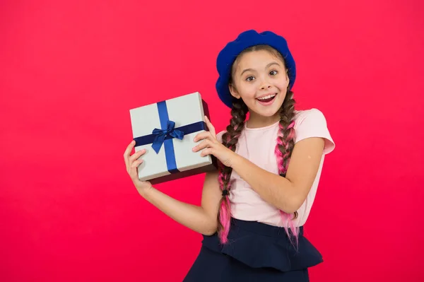 最好的圣诞礼物孩子为打开她的礼物而兴奋。孩子小女孩拿着礼物盒与丝带在红色背景。给女儿的圣诞礼物。可爱的小女孩收到节日礼物 — 图库照片