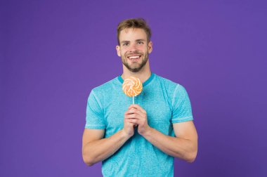 Adam büyük renkli tatlı lolipop yemek. Kıl adamla Lolipop sever. Yemek kavram hile. Şeker sağlık için zararlı. Adam lolipop şeker menekşe arka plan tutun. Çocukluk tadına. Lolipop eğlenceli