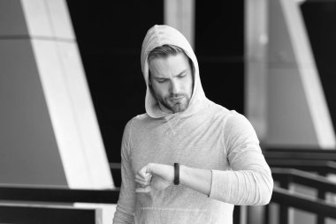 Biraz ara. Adam atlet zaman akıllı izle kentsel arka plan kontrol yüz konsantre. Atlet kıl ile akıllı saate benziyor. Sporcu pedometre gadget ile eğitim. Akıllı izle gadget concept