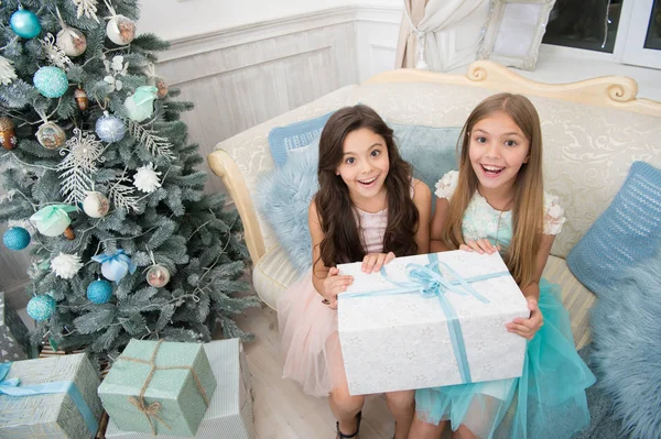 What a great surprise. Small cute girls received holiday gifts. Best toys and christmas gifts. Kids little sisters hold gifts boxes interior background. Children friends excited unpacking their gifts