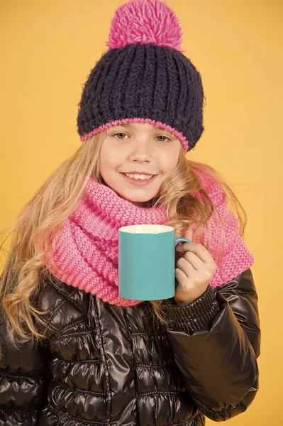 Girl in hat, pink scarf, black jacket with mug