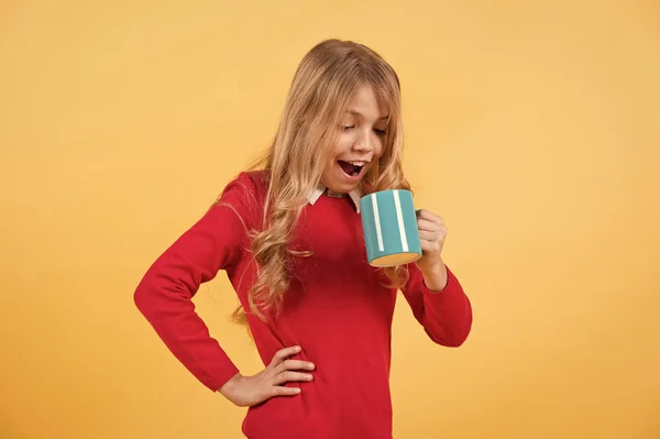 Niño con la cara sorprendida mantenga taza azul sobre fondo naranja —  Fotos de Stock