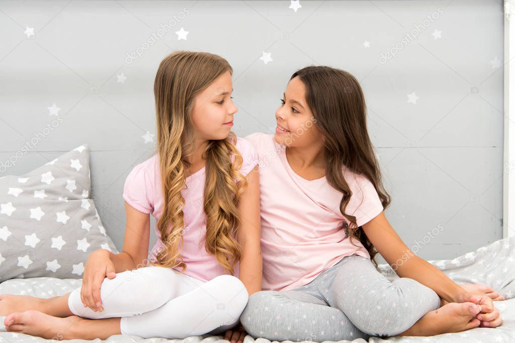 Sisters or best friends spend time together in bedroom. Girls having fun together. Girlish leisure. Sisters friends share gossips having fun at home. Pajamas party for kids. Siblings best friends