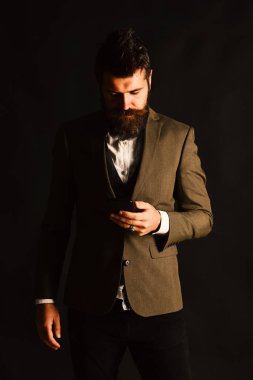 Sakallı bir işadamının cep telefonu var. Takım elbiseli adam.