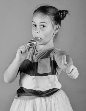 Çocuk şaşırmış yüzü ile yeşil zemin üzerine şeker ile poz veriyor.