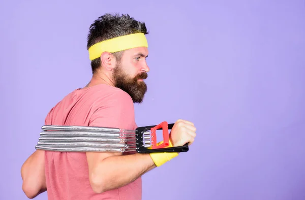 Man bearded athlete exercising with expander equipment. Sportsman wear retro outfit training violet background. Athlete sport instructor. Athlete training with chest expander. Athletics sport concept