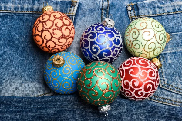 Christmas ornaments or decorations on denim pants background. Balls with glitter and shimmering decorative ornaments. Christmas decorations concept. Pick colorful decorations. Modern christmas decor