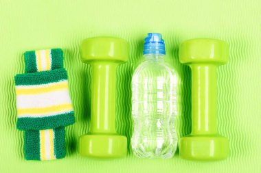 Bir çift yeşil halterli halterler ve bir şişe su..