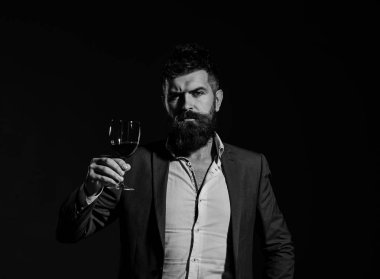 Takım elbiseli adam köpüklü kırmızı şarapla kadeh kaldırıyor.