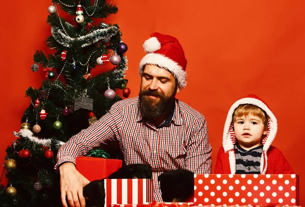 Padre e hijo con caras curiosas desempaquetan cajas en rojo — Foto de Stock