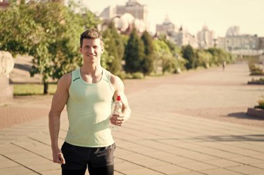 Şişe su ile gülümseyerek mutlu bir adam atlet