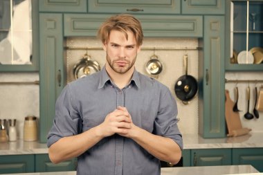 Adam ciddi bir yüz ile stand ile mutfakta katlanmış parmak