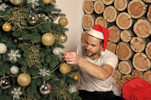 Man in santa claus hat decorate Christmas tree — Stock Photo, Image