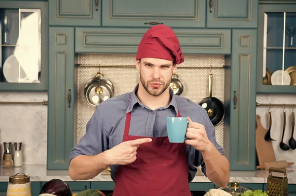 Хлопець вказує пальцем на синю чашку на кухні — стокове фото