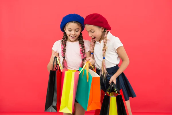 A gyerekek élvezni vásárlás piros háttér. Látogat a mall ruházat. Kedvezmény és értékesítési koncepció. Gyerekek aranyos lány bevásárló táska tartsuk. Vásárlási kedvezmény a szezonban. Különleges ajánlat. Nagy nap vásárlás — Stock Fotó