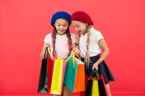 Los niños disfrutan comprando fondo rojo. Visitando el centro comercial de ropa. Concepto de descuento y venta. Niños chicas lindas sostienen bolsas de compras. Compras temporada de descuento. Oferta especial. Gran día para hacer compras — Foto de Stock