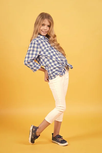 Chica en camisa a cuadros, pantalones, zapatillas posan sobre fondo naranja — Foto de Stock