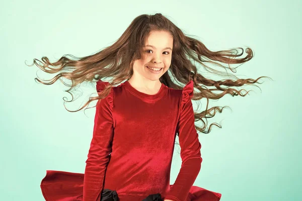 Malá dívka úsměv s létáním vlasy na modrém pozadí, móda — Stock fotografie