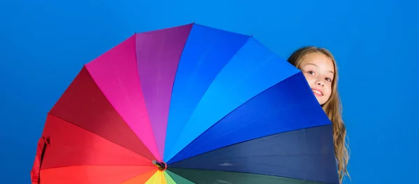 Colorful umbrella accessory. Weather forecast concept. Stay positive though rainy day. Brighten up life. Kid peek out colorful rainbow umbrella. Color your life. Girl cheerful hide behind umbrella — Stock Photo, Image