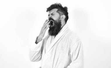 Genç adam ağzı geniş açık esneme. Hippi beyaz bornoz beyaz arka plan üzerinde izole içinde. Partiden sonra sabahları yorgun maço